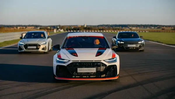 Trzy samochody Audi RS 8 na torze wyścigowym. Biały RS 8 z czerwonymi akcentami na pierwszym planie, za nim biały i czarny RS 8.