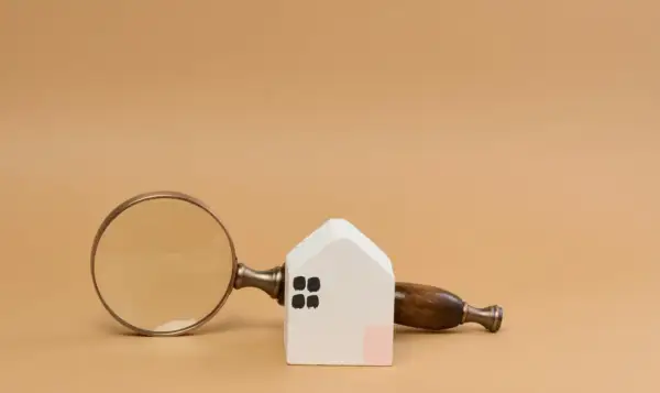 Lente d'ingrandimento su una casetta bianca, per capire cos'è una visura catastale e i dettagli di un immobile.