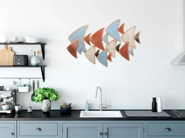 Décoration murale cuisine : un banc de poissons stylisés aux couleurs pastel et terreuses orne le mur blanc au-dessus d'un évier moderne.