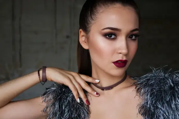 Elegancki makijaż dla brązowych oczu i ciemnych włosów. Ciemne usta i smoky eyes podkreślają urodę modelki.