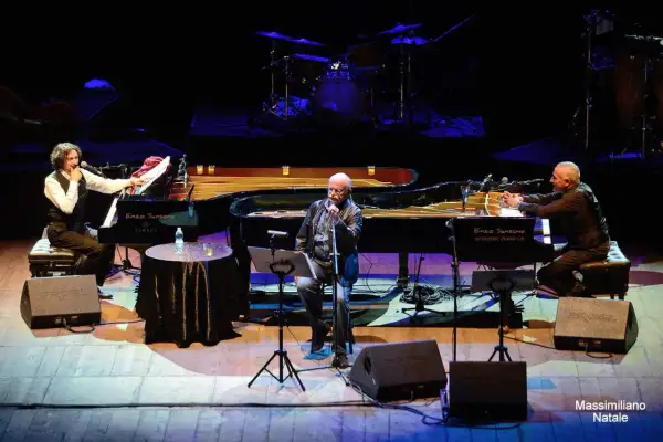 Sergio Cammariere e Enzo Sansone, mano nella mano, suonano i loro pianoforti in un concerto.