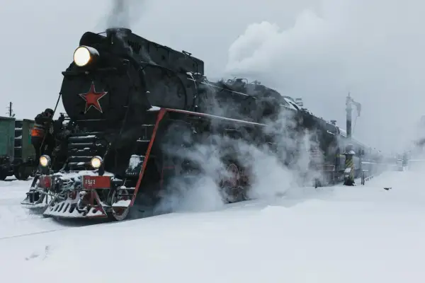 Parowóz z czerwoną gwiazdą, gotowy do podróży przez śnieżny krajobraz. To obraz, który przywodzi na myśl legendarną kolej transsyberyjską.
