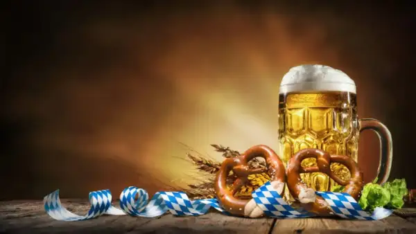 Boccale di birra dorata, pretzel e nastri bavaresi evocano la storia dell'Oktoberfest.