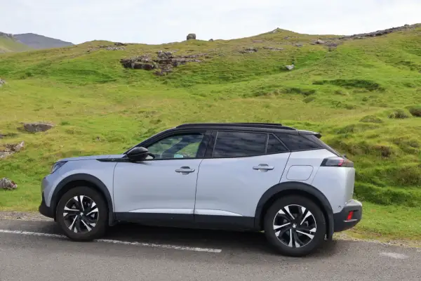 Silver Peugeot 2008 parkerad vid en grön sluttning, kanske med ett litet problem.