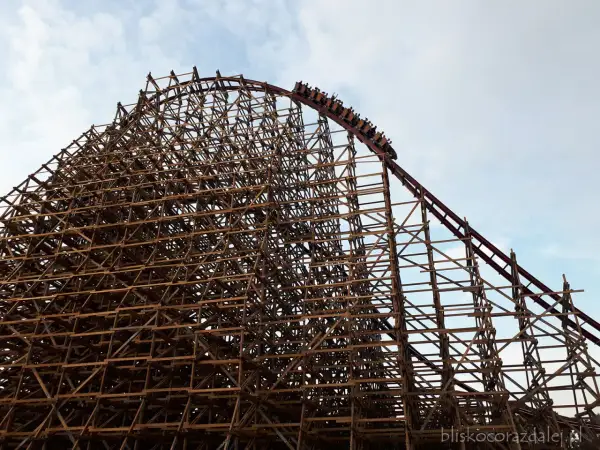 Drewniana konstrukcja rollercoastera w Energylandii, z wagonikami wjeżdżającymi na szczyt. Czy Energylandia jest otwarta w deszcz?