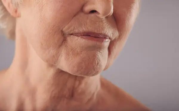 Primo piano del volto di un'anziana, con labbra sottili e rughe della marionetta che raccontano storie di vita.