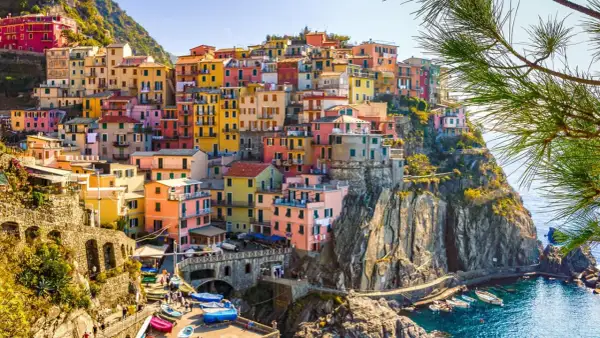 Färgstarka hus klättrar uppför klipporna vid havet i Italien. En vacker vy som ger fakta om Italien.