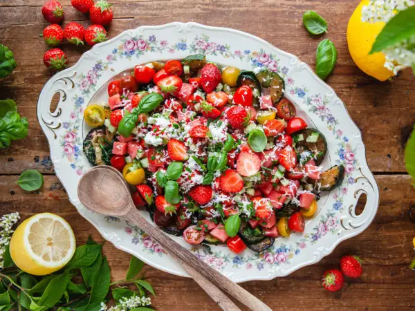 En härlig somrig sallad med jordgubbar, vattenmelon, tomater och basilika på ett vackert fat.