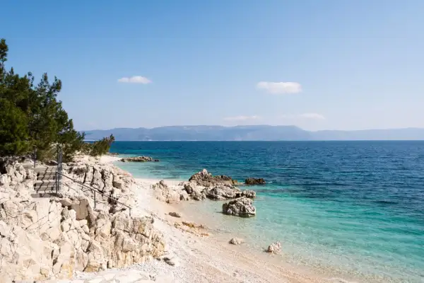 Kamienista plaża z turkusową wodą i schodami prowadzącymi do morza. Idealne miejsce na odkrywanie uroków Chorwacji, Istria atrakcje.