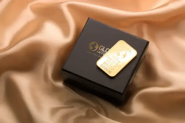 Złoto dukatowe próba 999.9 na czarnym pudełku, prezentujące 100g sztabki z logo Global Intergold.