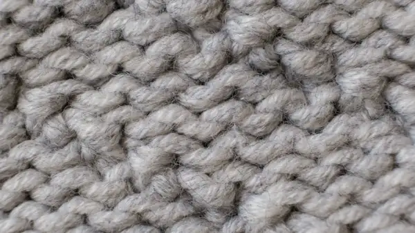 Nahaufnahme einer dicken, grauen Stricktextur. Die einzelnen Fäden sind flauschig und weich, ideal für das Mohair waschen.