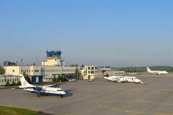 Lotnisko Katowice z wieżą kontroli lotów i samolotami na płycie. Które lotnisko większe Kraków czy Katowice?