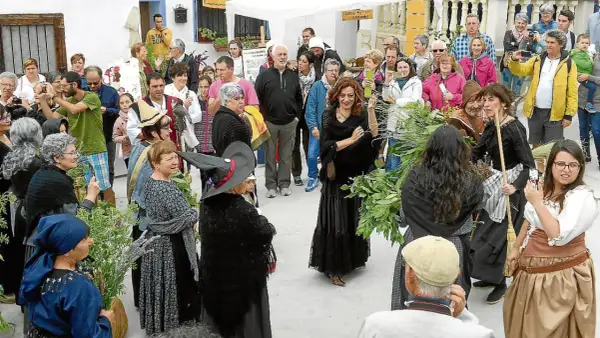 Gente celebra la fiesta de las brujas en Trasmoz. Mujeres vestidas de negro y con sombreros de bruja, rodeadas de hierbas y flores.