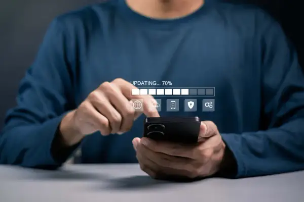 Osoba korzysta z telefonu, na którym widać pasek postępu "UPDATING... 70%" i ikony związane z aktualizacjami systemu Android.