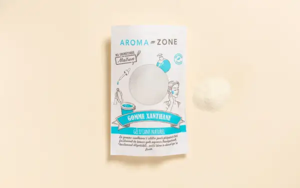 Un sachet de gomme xanthane Aroma-Zone, un gélifiant naturel pour vos cosmétiques maison. Une poudre fine à côté du paquet.