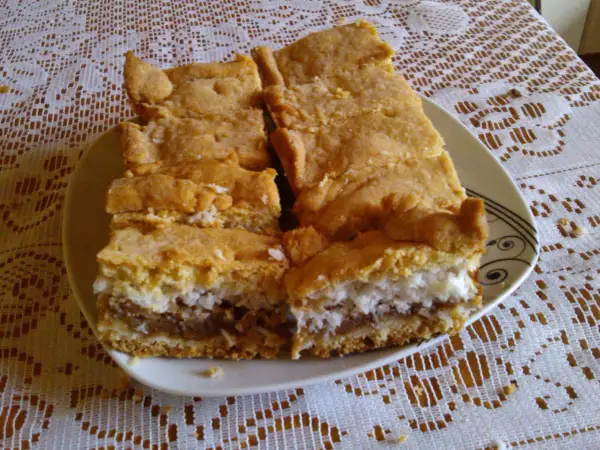 Pyszne ciasto z jabłkami i kokosem, pokrojone na kawałki, leży na talerzu.