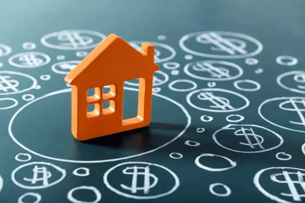 Casa naranja sobre fondo oscuro con símbolos de dólar dibujados. BBVA tasación de inmuebles.