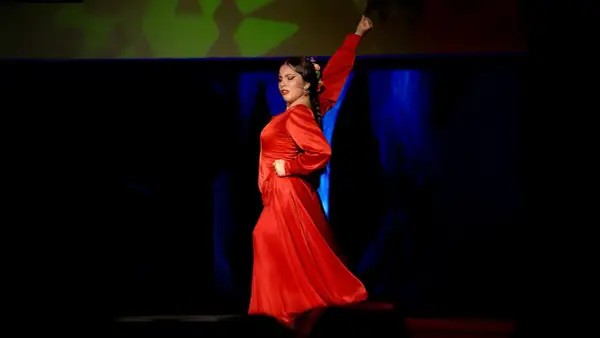 Una bailaora de flamenco, vestida de rojo pasión, evoca la fuerza y elegancia de los grupos de sevillanas.
