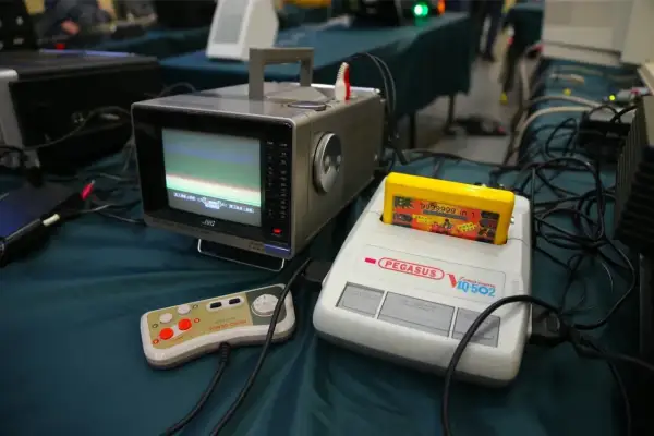 Stary monitor JVC, konsola Pegasus IQ-502 z żółtą kasetą i kontroler Micro Genius.