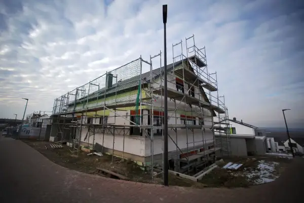 Haus im Bau mit Gerüst und Dämmung unter bewölktem Himmel.