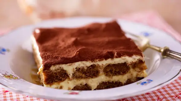 Ein Stück cremiges Tiramisu, das klassische italienische Dessert, bestäubt mit Kakao.