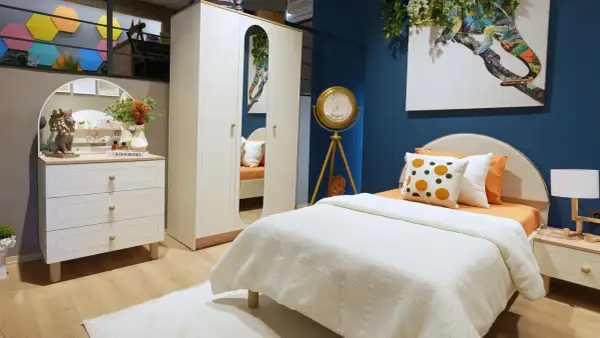 Ein gemütliches boho style jugendzimmer mit weißem Bett, Kleiderschrank und Kommode. Ein buntes Chamäleon-Bild ziert die Wand.