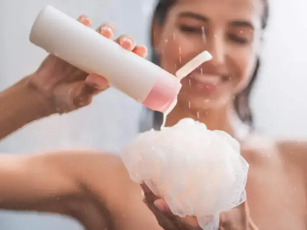 Mujer sonriente aplica shower cream para que sirve: limpieza e hidratación para una piel suave y radiante.