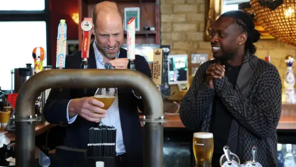 Uomo che versa una pinta di birra, mentre un altro uomo sorride.