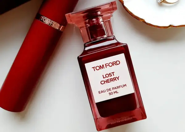 Elegancka butelka perfum Tom Ford Lost Cherry 50 ml w odcieniu głębokiej czerwieni, obok czerwonego opakowania.