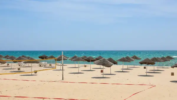 Piękna plaża w Tunezji we wrześniu. Słoneczna pogoda, turkusowe morze i rzędy parasoli zapraszają do relaksu.