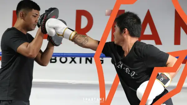 Two boxers train in a ring, one holding pads for the other's punch. This image shows the dedication required to reach advanced boxing levels.