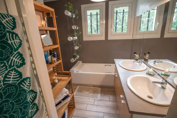 Salle de bain moderne avec baignoire, double vasque et étagères en bambou. Une idée pour relooker meuble salle de bain avec des plantes suspendues.