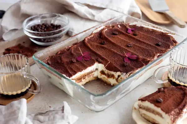En härlig tiramisu i glasform, pudrad med kakao och dekorerad med kaffebönor och blommor. Perfekt för tips på bakning!