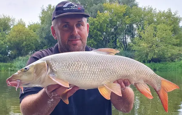 Wędkarz z okazałym kleniem złowionym nad jeziorem w Zabrzu.