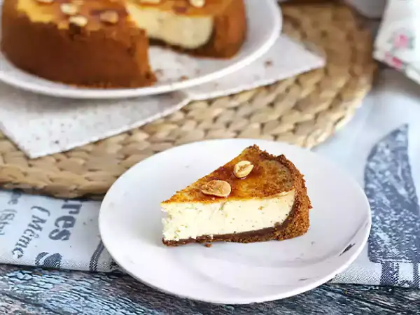 Tranche de cheesecake ricotta onctueux, garnie de noisettes caramélisées. Un délice gourmand.