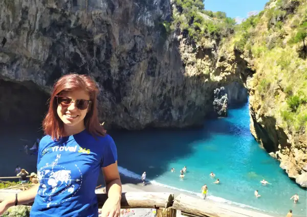 Giovane donna sorride in una baia con acqua turchese, uno dei tanti posti da visitare in Calabria.