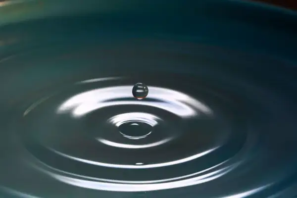 Kropla wody zawieszona w powietrzu, tworząca idealne kręgi na powierzchni. Jakby zatrzymany kadr z filmu łzowego, pełen emocji i refleksji.