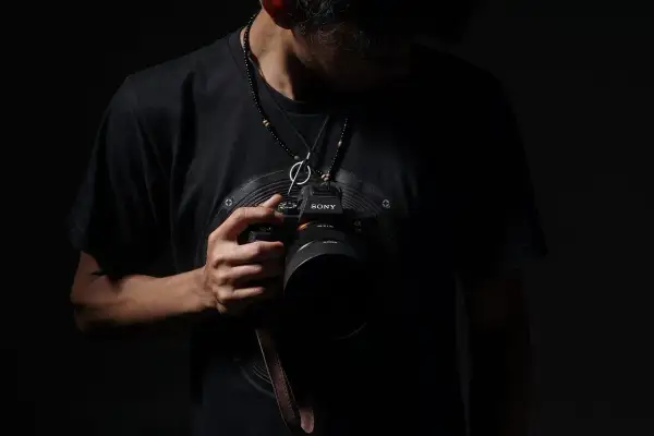 Mężczyzna w czarnej koszulce trzyma aparat Sony. Może to być jego zgłoszenie do konkursu fotograficznego.