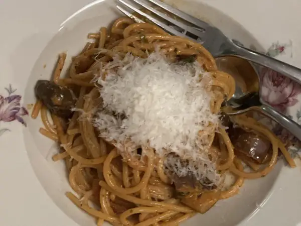 En tallrik spaghetti med aubergine och rikligt med riven ost. En smak av siciliansk mat som ser utsökt ut.