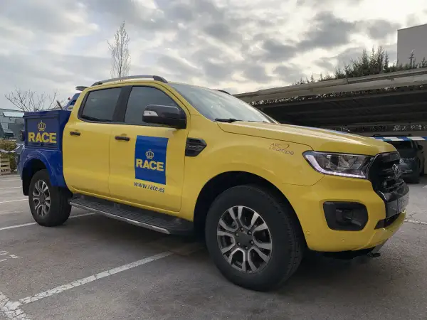Camioneta amarilla y azul del RACE, lista para la acción. Su diseño es ideal para cualquier tipo de carrera o servicio.