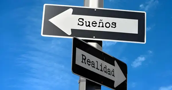 Señales de tráfico apuntan en direcciones opuestas: una hacia "Sueños" y otra hacia "Realidad". Frases de sueños y realidad.