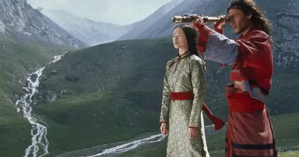 Para w tradycyjnych strojach, w tle górzysty krajobraz. Scena z kina azjatyckiego, gdzie mężczyzna przez lunetę obserwuje horyzont.