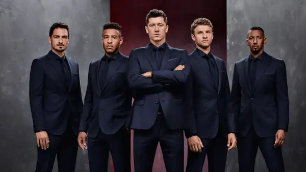 Pięciu mężczyzn w granatowych garniturach, prezentujących elegancję marki Hugo Boss.