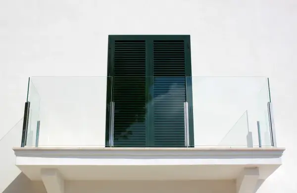Nowoczesny balkon z przeszkloną balustradą. Okapnik nad oknem zapewnia ochronę przed deszczem.