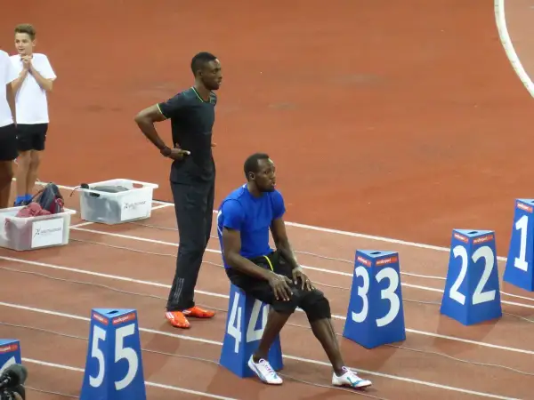 Usain Bolt, siedzący i stojący na bieżni, przypomina o jego rekordowej prędkości, która osiągnęła ponad 44 km/h.