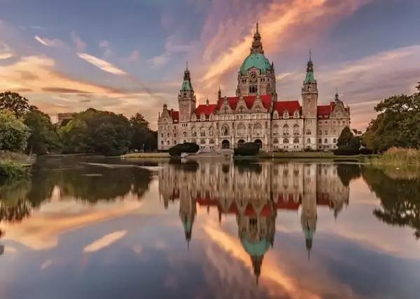 Nowy Ratusz w Hanowerze, jeden z najpiękniejszych zamków w Niemczech, odbija się w spokojnej tafli jeziora o zachodzie słońca.