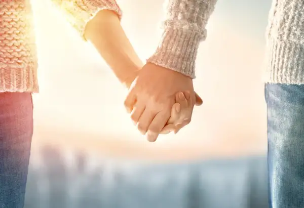Manos entrelazadas bajo un sol cálido, un símbolo de una profunda **relación kármica** que trasciende el tiempo.