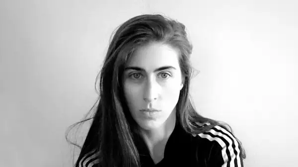 Ritratto in bianco e nero di Mara Oscar Cassiani, con lunghi capelli castani e indosso una felpa con le iconiche tre strisce.