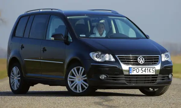 Czarny Volkswagen Touran 2004 z kierowcą w kapturze, widok z przodu.