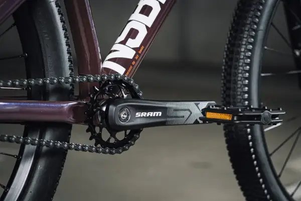 Zbliżenie na rowerowy mechanizm korbowy SRAM i łańcuch. Tabela przełożeń rowerowych jest kluczowa dla optymalnego pedałowania.